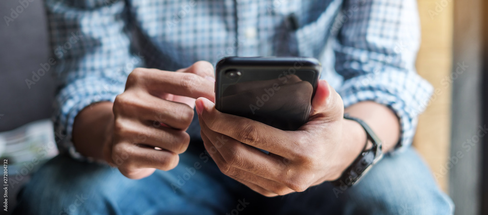 Young casual Businessman holding and using smartphone for sms messages, hipster man typing touchscreen cell phone in the cafe. business, lifestyle, technology and Social media network concept